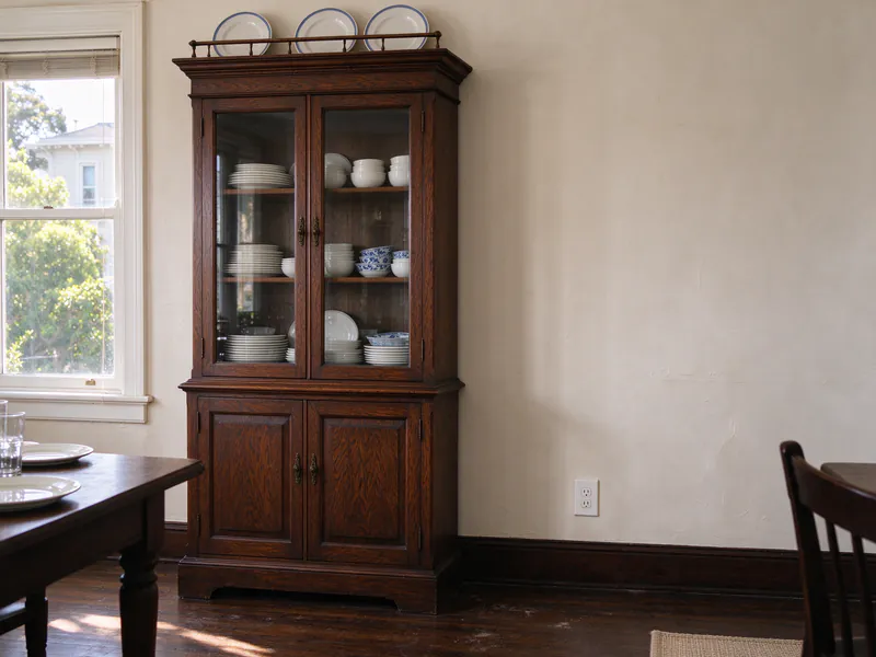 An Edwardian dining room with a built-in glass-front cabinet and a new outlet low on the plaster wall